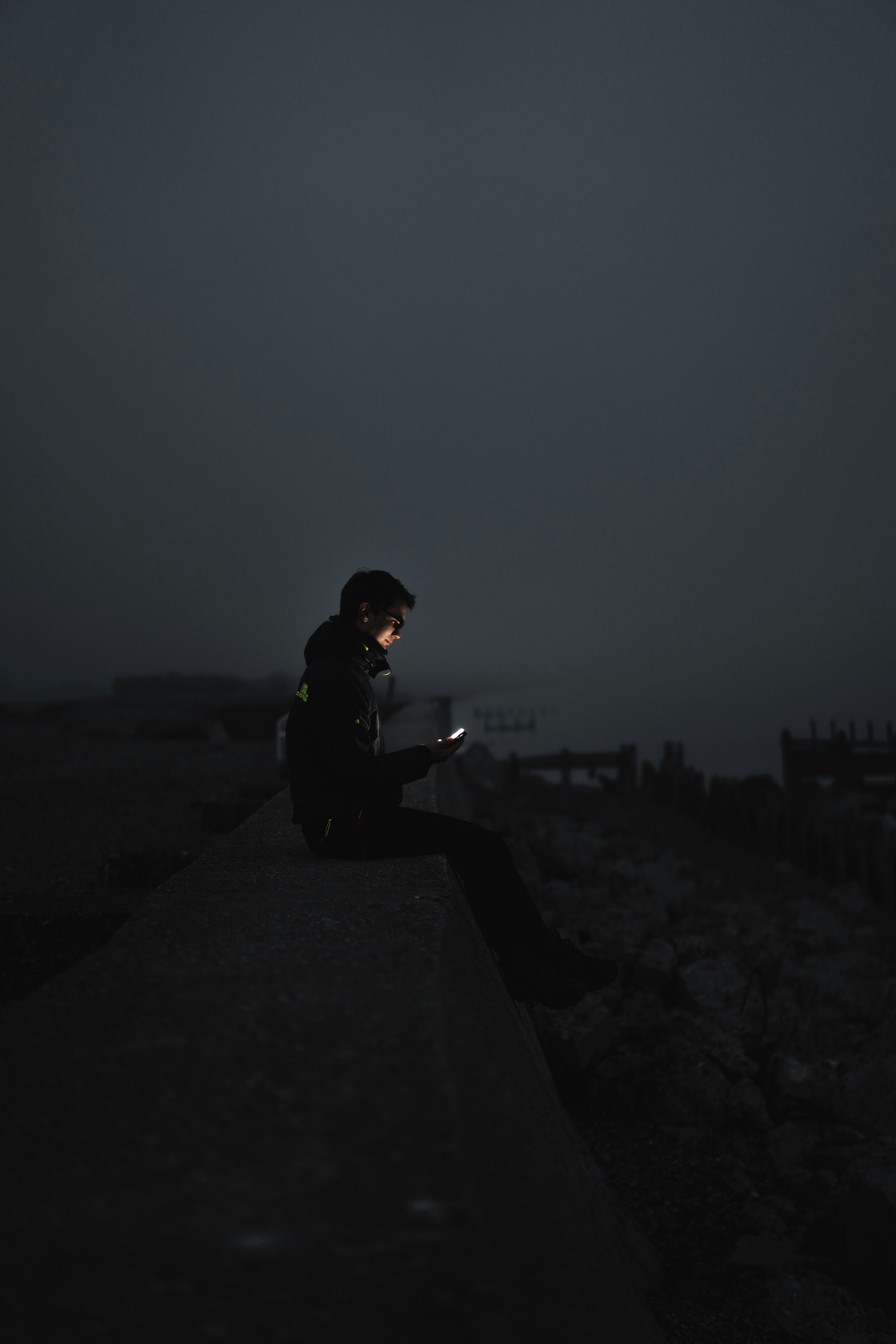 man in black jacket sitting on the ground during night time